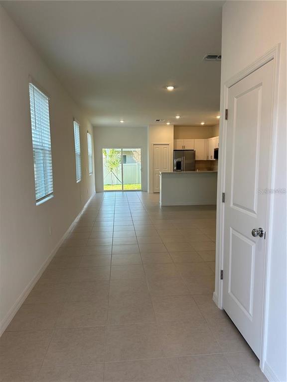 An open-concept living area features light tile flooring, white walls, and a kitchen with cabinets — 2655 BUTTERCUP LUCINE LANE, RUSKIN, FL