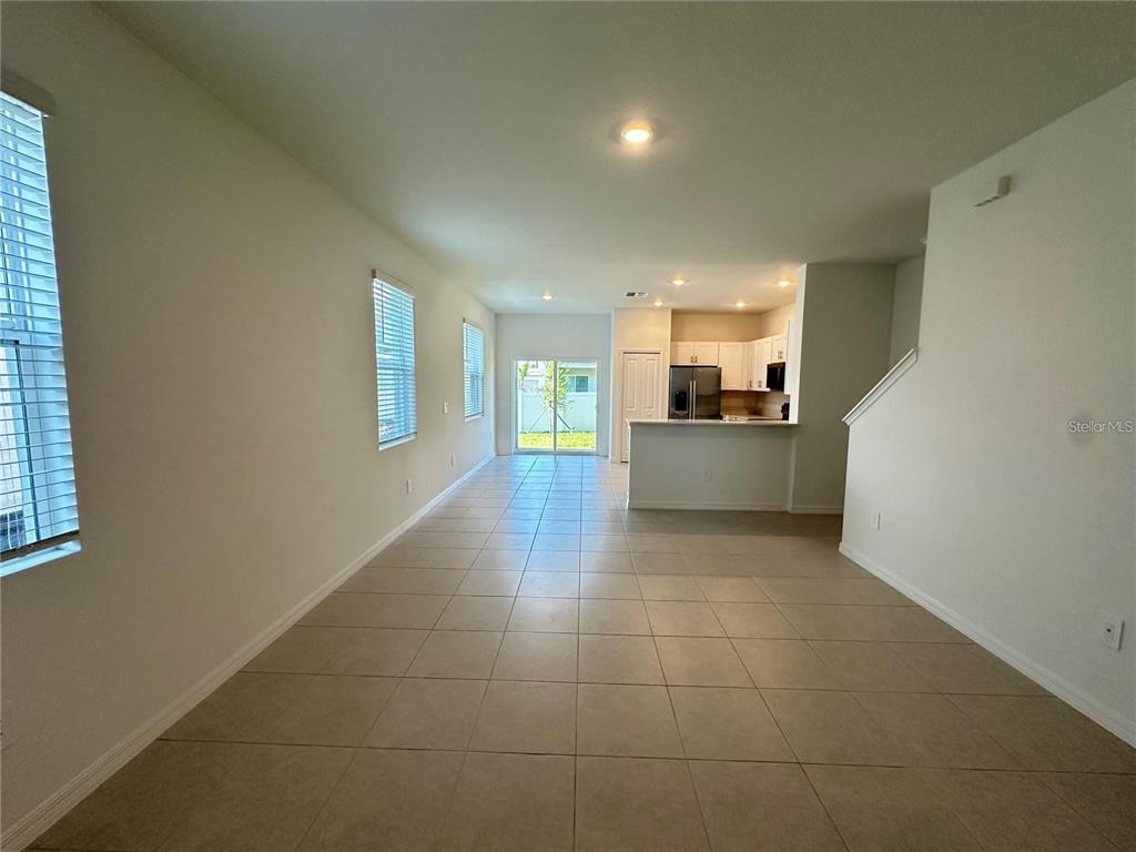 An open-concept living area features tile flooring, a kitchen with white cabinets, and sliding doors — 2655 BUTTERCUP LUCINE LANE, RUSKIN, FL
