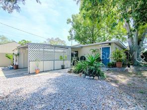 A single-story house with a gravel driveway, a lattice-enclosed carport, and a blue front door — 5617 GULFPORT BOULEVARD S, GULFPORT, FL