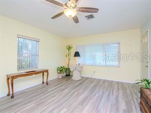 A living room with light-colored walls, wood-look flooring, a ceiling fan, and two windows — 5617 GULFPORT BOULEVARD S, GULFPORT, FL