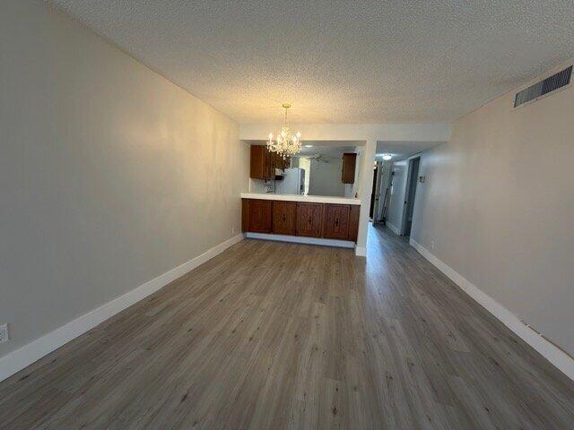An open living area features light wood-look flooring, a chandelier, and a kitchen pass-through window — 6021 Coral Lake Drive # 209, Margate FL 33063, MARGATE, FL