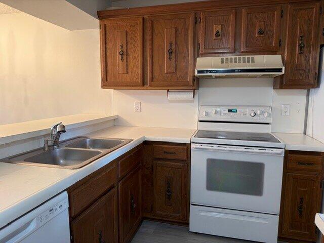 A kitchen with wood cabinets, white countertops, a white stove, and a double-basin sink — 6021 Coral Lake Drive # 209, Margate FL 33063, MARGATE, FL