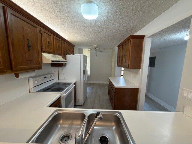 A kitchen features wood cabinets, white appliances, and a stainless steel double-basin sink — 6021 Coral Lake Drive # 209, Margate FL 33063, MARGATE, FL