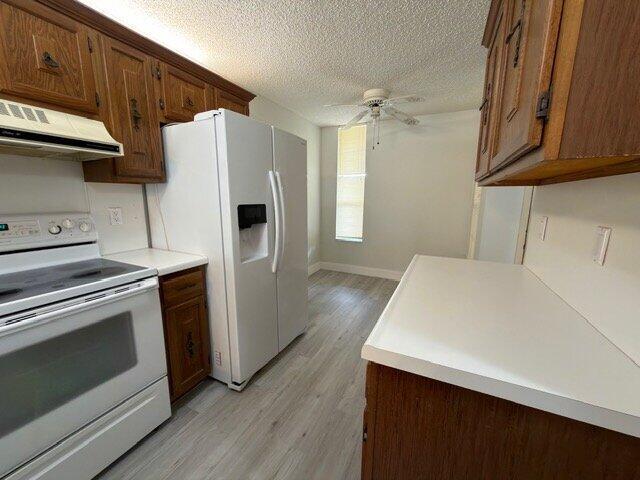 A kitchen features wood cabinets, a white stove, a side-by-side refrigerator, and light flooring — 6021 Coral Lake Drive # 209, Margate FL 33063, MARGATE, FL