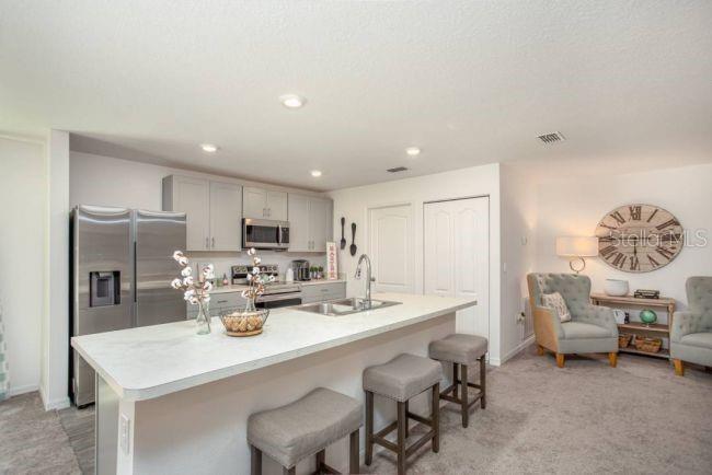 A kitchen with light gray cabinets, stainless steel appliances, and a central island with stools — 10072 N CONRAD POINT, CITRUS SPRINGS, FL