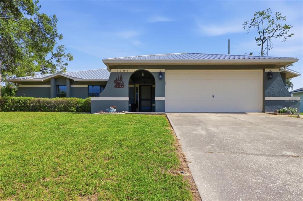 A single-story house with a gray exterior, metal roof, and an attached two-car garage — 1900 W ALHAMBRA DRIVE, CITRUS SPRINGS, FL