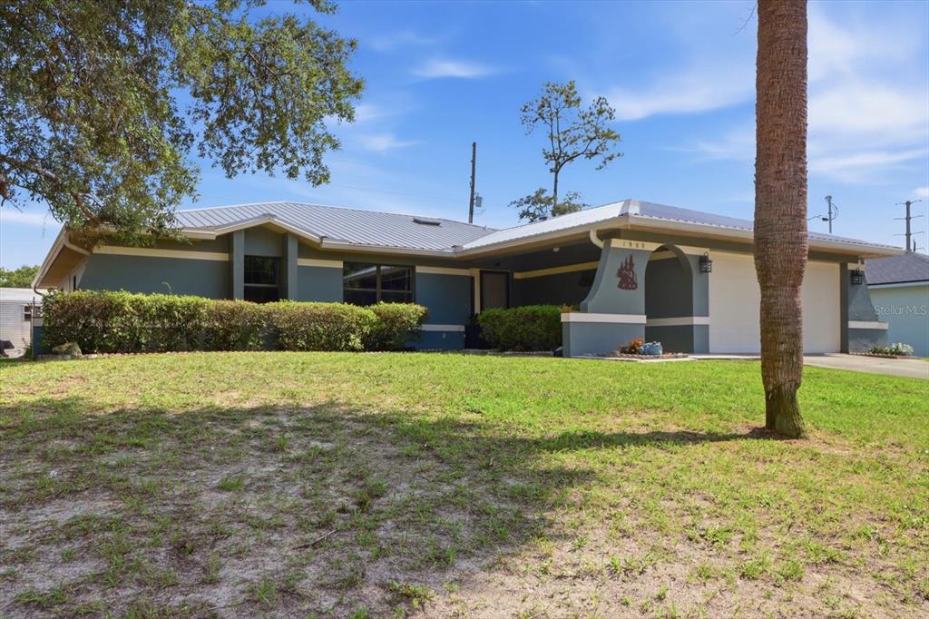 A single-story house with a blue exterior, metal roof, and a two-car garage — 1900 W ALHAMBRA DRIVE, CITRUS SPRINGS, FL