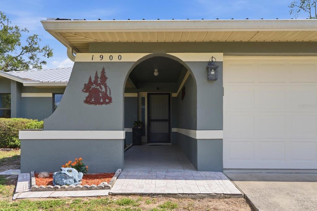 The exterior of a house features a gray stucco facade, a covered entryway, and a garage — 1900 W ALHAMBRA DRIVE, CITRUS SPRINGS, FL