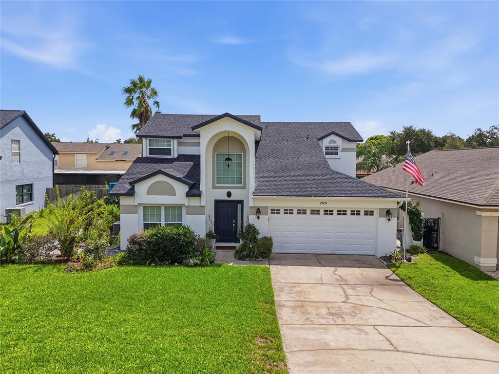 A two-story suburban house with a white garage, arched entryway, and a front lawn — 2909 SOMERSWORTH COURT, ORLANDO, FL