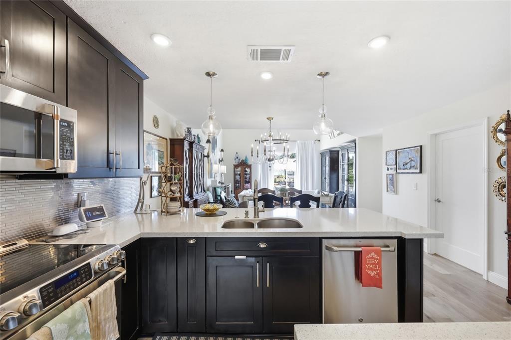 A kitchen with dark cabinets, stainless steel appliances, and a quartz-topped island with a sink — 2909 SOMERSWORTH COURT, ORLANDO, FL