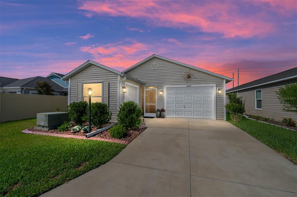 A single-story house with beige vinyl siding, a white garage door, and a concrete driveway — 1442 JOSHUA COURT, THE VILLAGES, FL