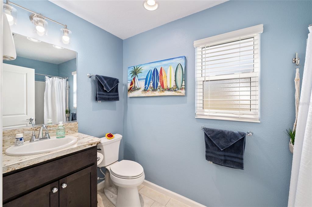 A bathroom with light blue walls, a dark wood vanity, and a surfboard wall art piece — 1442 JOSHUA COURT, THE VILLAGES, FL