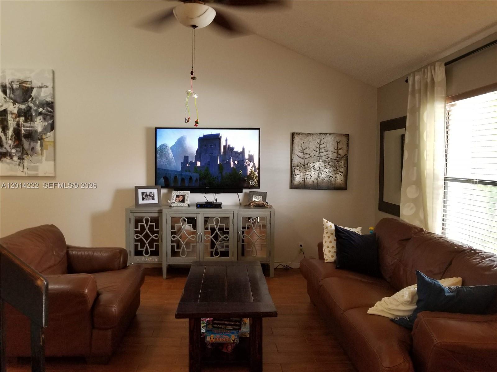 A living room features brown leather furniture, a television on a console, and vaulted ceilings — 8509 Shadow Ct # 11, Coral Springs FL 33071, CORAL SPRINGS, FL