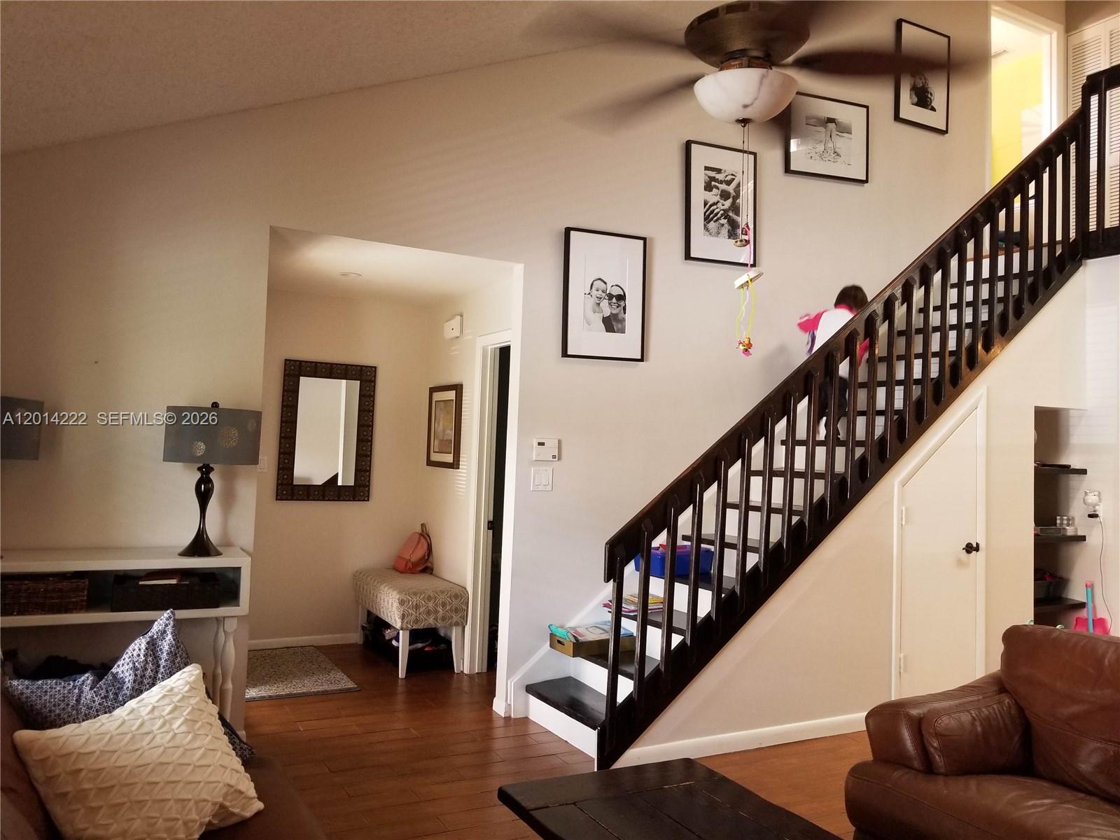 A living room features a wooden staircase, hardwood floors, and framed wall art — 8509 Shadow Ct # 11, Coral Springs FL 33071, CORAL SPRINGS, FL