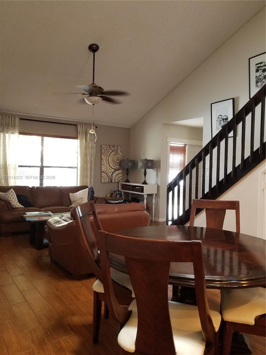 A living room with a brown leather sofa, dining table, and staircase with black railings — 8509 Shadow Ct # 11, Coral Springs FL 33071, CORAL SPRINGS, FL