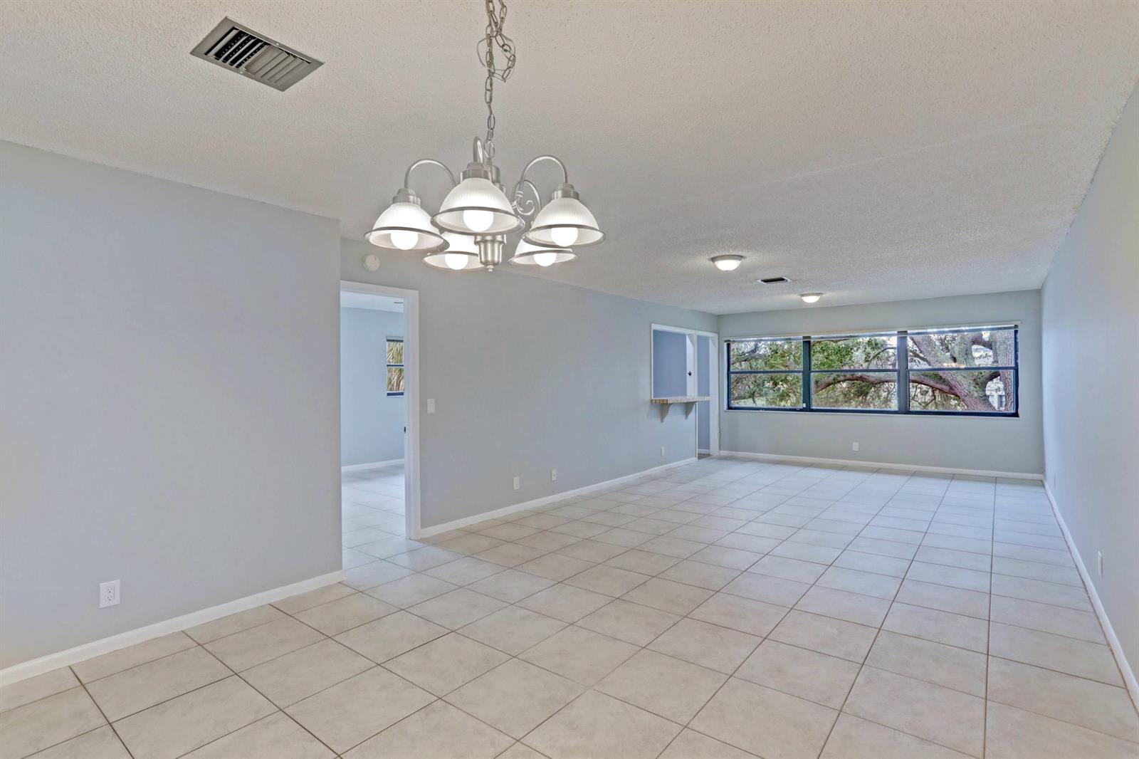 An empty room with light gray walls, tile flooring, a chandelier, and a large window — 3011 SW 21st Terrace # 382a, Delray Beach FL 33445, DELRAY BEACH, FL