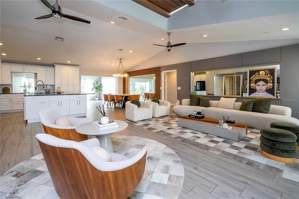 An open-concept living area features a wood-paneled tray ceiling, light wood flooring, and modern furniture — 10129 LONE TREE LANE, ORLANDO, FL