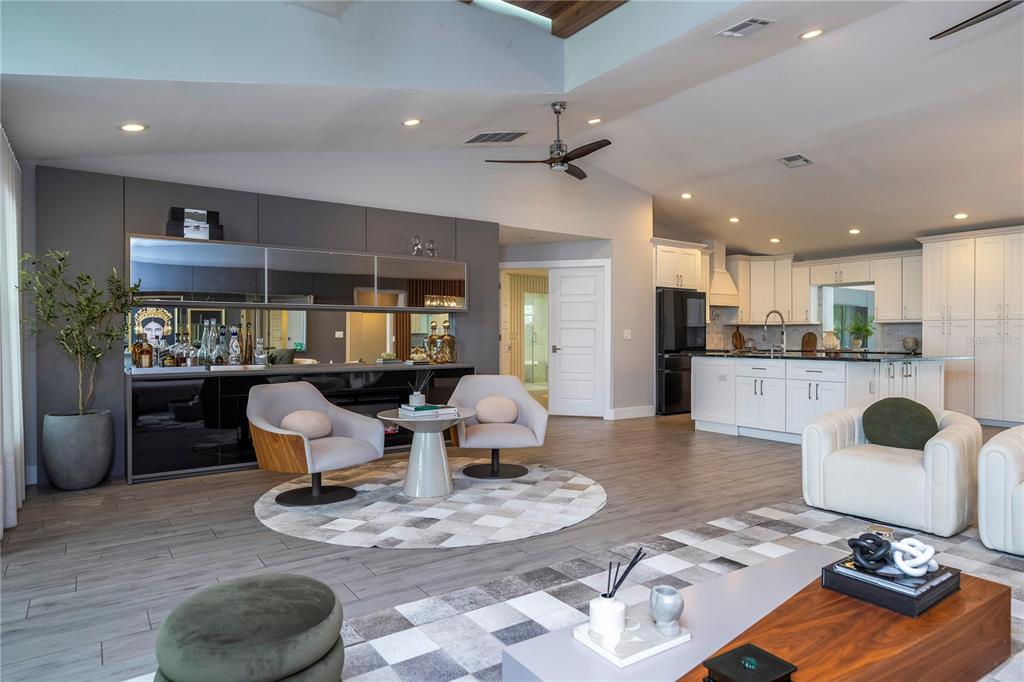 A modern open-concept living room features a kitchen, dining area, and neutral-toned furniture — 10129 LONE TREE LANE, ORLANDO, FL