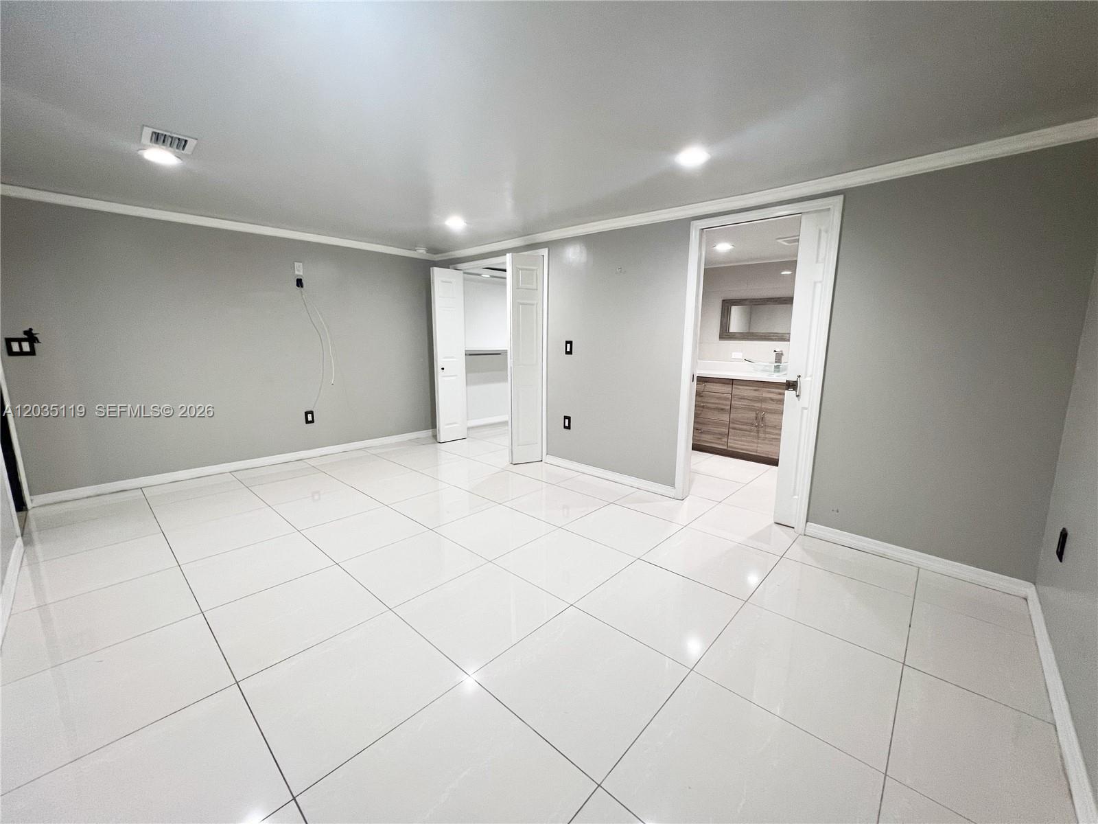 A bedroom with gray walls, white tile flooring, a closet, and an attached bathroom — 9615 NW 3rd Ave, Miami FL 33150, MIAMI, FL