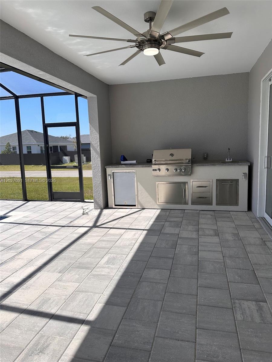 A covered outdoor patio features a built-in kitchen with a grill, sink, and refrigerator — 314 NW 16, Cape Coral FL 33993, CAPE CORAL, FL