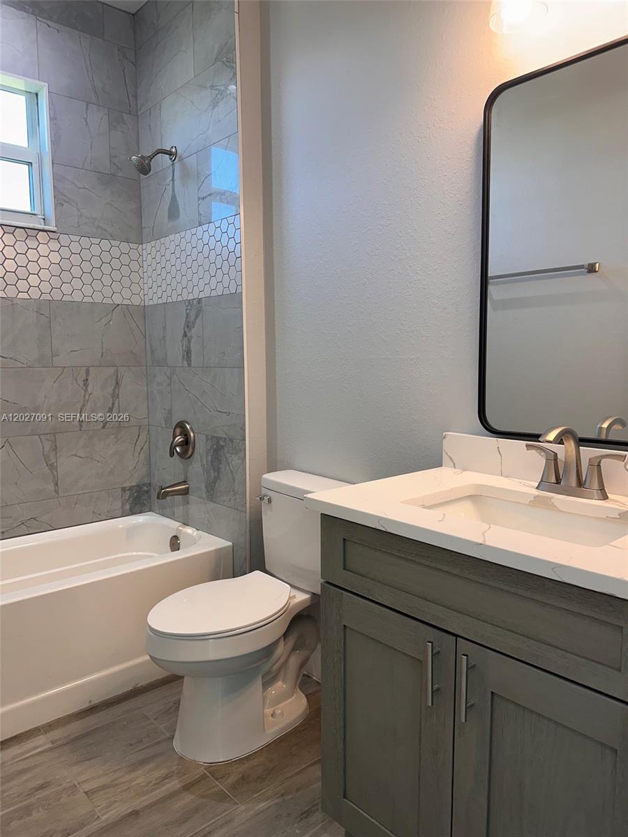 A bathroom features a gray vanity, a toilet, and a tub with gray tile walls — 314 NW 16, Cape Coral FL 33993, CAPE CORAL, FL