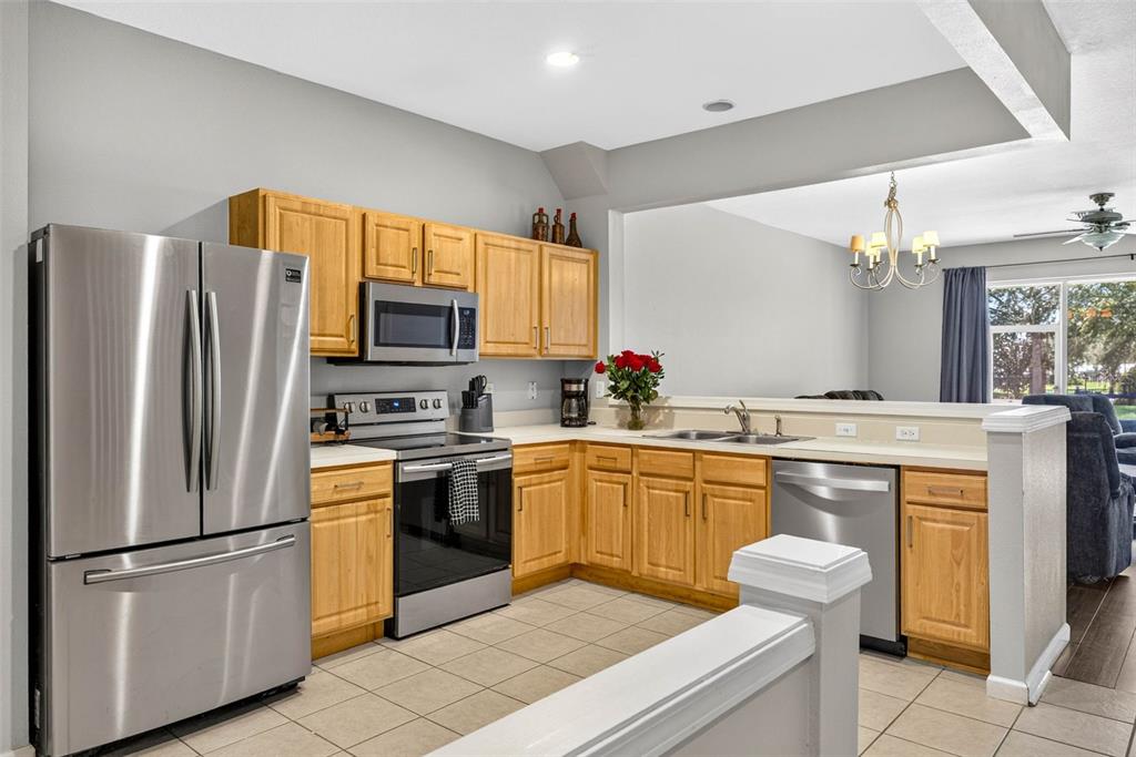 A kitchen features stainless steel appliances, light wood cabinets, and tile flooring — 26624 CHIMNEY SPIRE LANE, WESLEY CHAPEL, FL