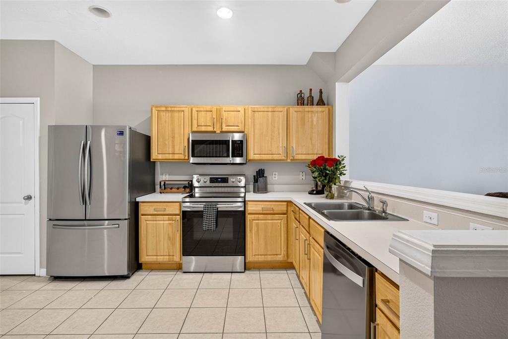 A kitchen features light wood cabinets, stainless steel appliances, and a white countertop — 26624 CHIMNEY SPIRE LANE, WESLEY CHAPEL, FL