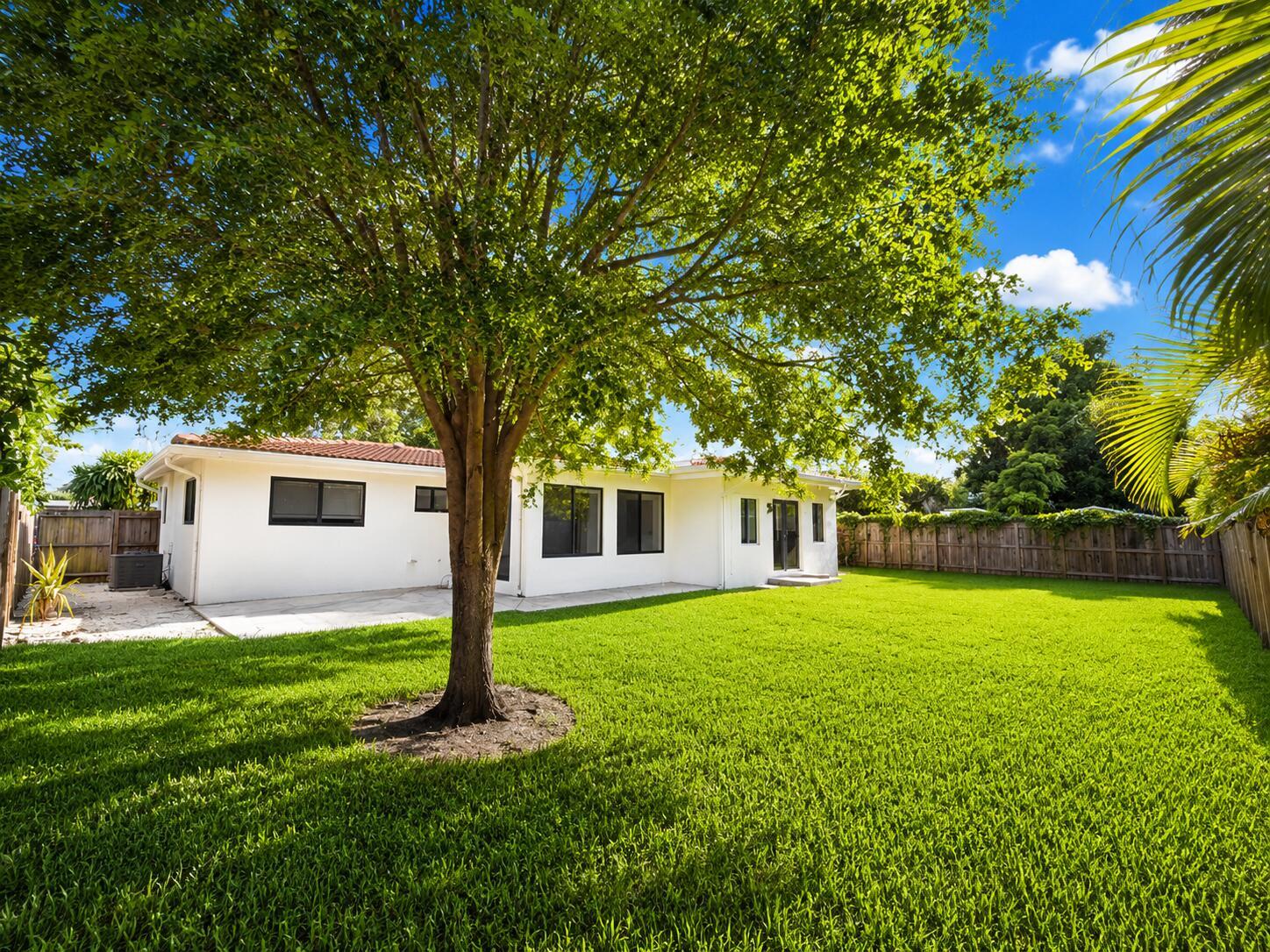 A white house with a large backyard, a central tree, and a wooden fence — 909 SE 14th Drive, Deerfield Beach FL 33441, DEERFIELD BEACH, FL