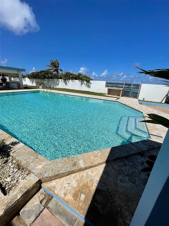 An outdoor swimming pool with stone decking sits in a yard with a white wall — 681 N KM 11.7 ISLOTE, ARECIBO, PR