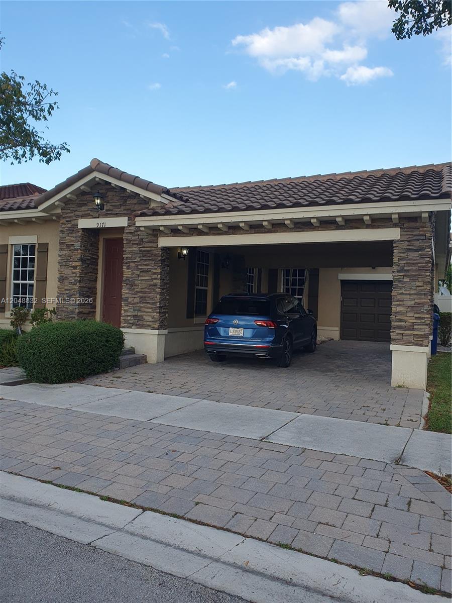 A single-story house features a stone facade, a covered carport, and a paved driveway — 9171 SW 169th PL # 0, Miami FL 33196, MIAMI, FL
