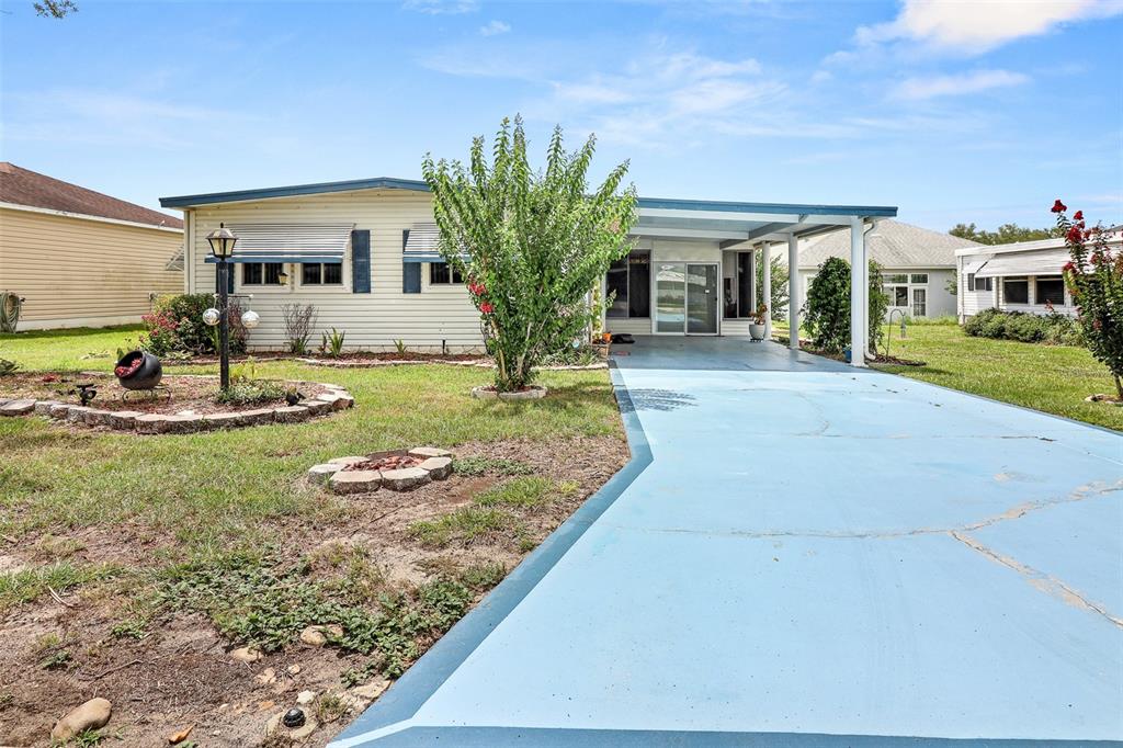 A single-story house with light siding, a blue-painted driveway, and a covered carport — 919 WEEPING WILLOW AVENUE, LADY LAKE, FL