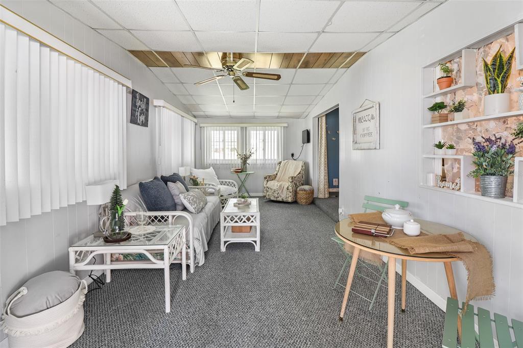 A sunroom features gray carpeting, white paneled walls, a ceiling fan, and a dining area — 919 WEEPING WILLOW AVENUE, LADY LAKE, FL