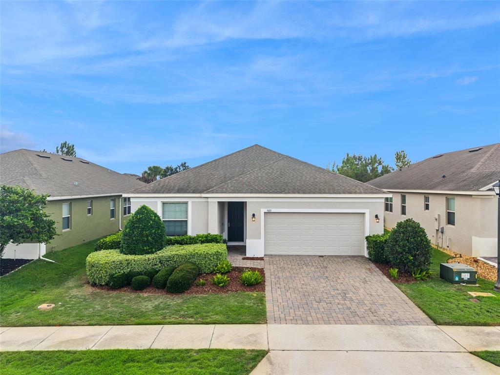 A single-story house with a paved driveway, a two-car garage, and manicured landscaping — 1013 SADIE RIDGE ROAD, CLERMONT, FL
