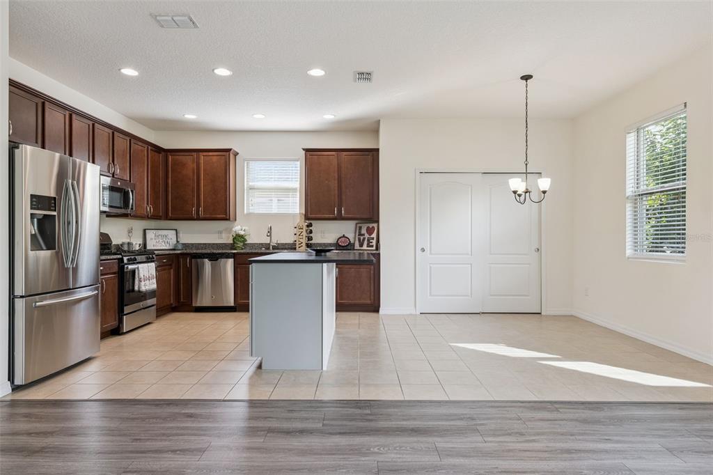 A kitchen with dark wood cabinets, stainless steel appliances, a center island, and tile flooring — 1013 SADIE RIDGE ROAD, CLERMONT, FL