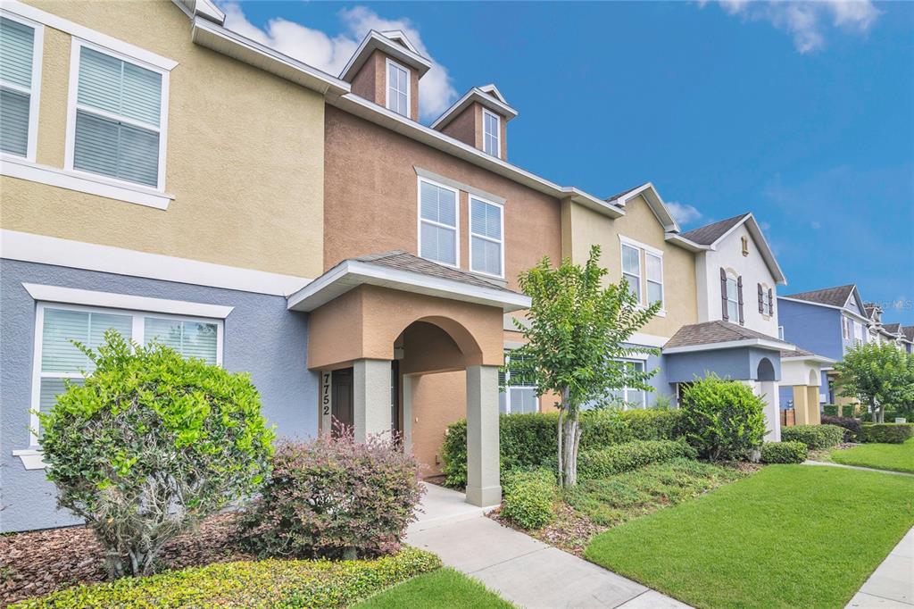 A multi-story townhouse exterior features a tan and blue facade with a covered entryway — 7752 RIGBY STREET, WINDERMERE, FL