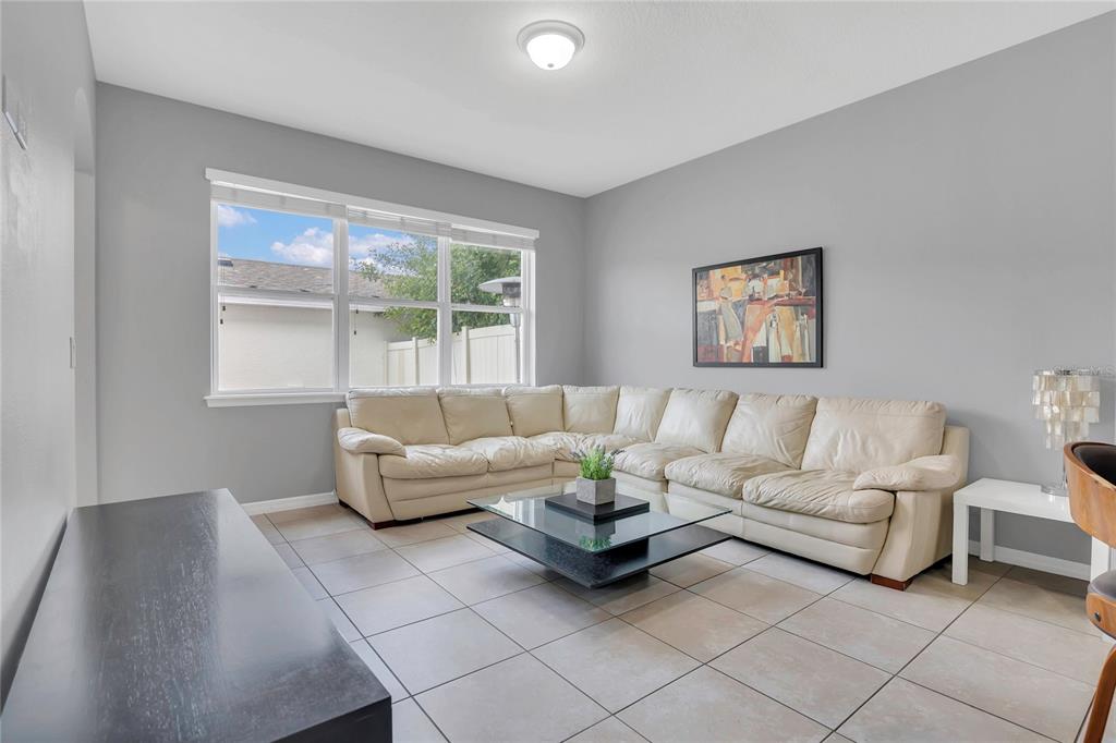 A living room features light gray walls, tile flooring, a large sectional sofa, and a window — 7752 RIGBY STREET, WINDERMERE, FL