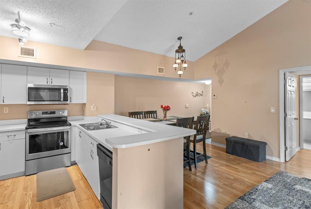 A kitchen with white cabinets and stainless steel appliances opens to a dining area — 3874 Lyons Road # 6, Coconut Creek FL 33073, COCONUT CREEK, FL