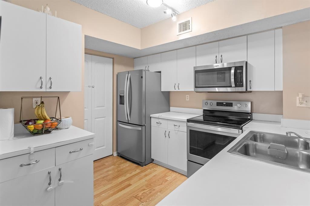 A kitchen features white cabinets, stainless steel appliances, and light wood flooring — 3874 Lyons Road # 6, Coconut Creek FL 33073, COCONUT CREEK, FL