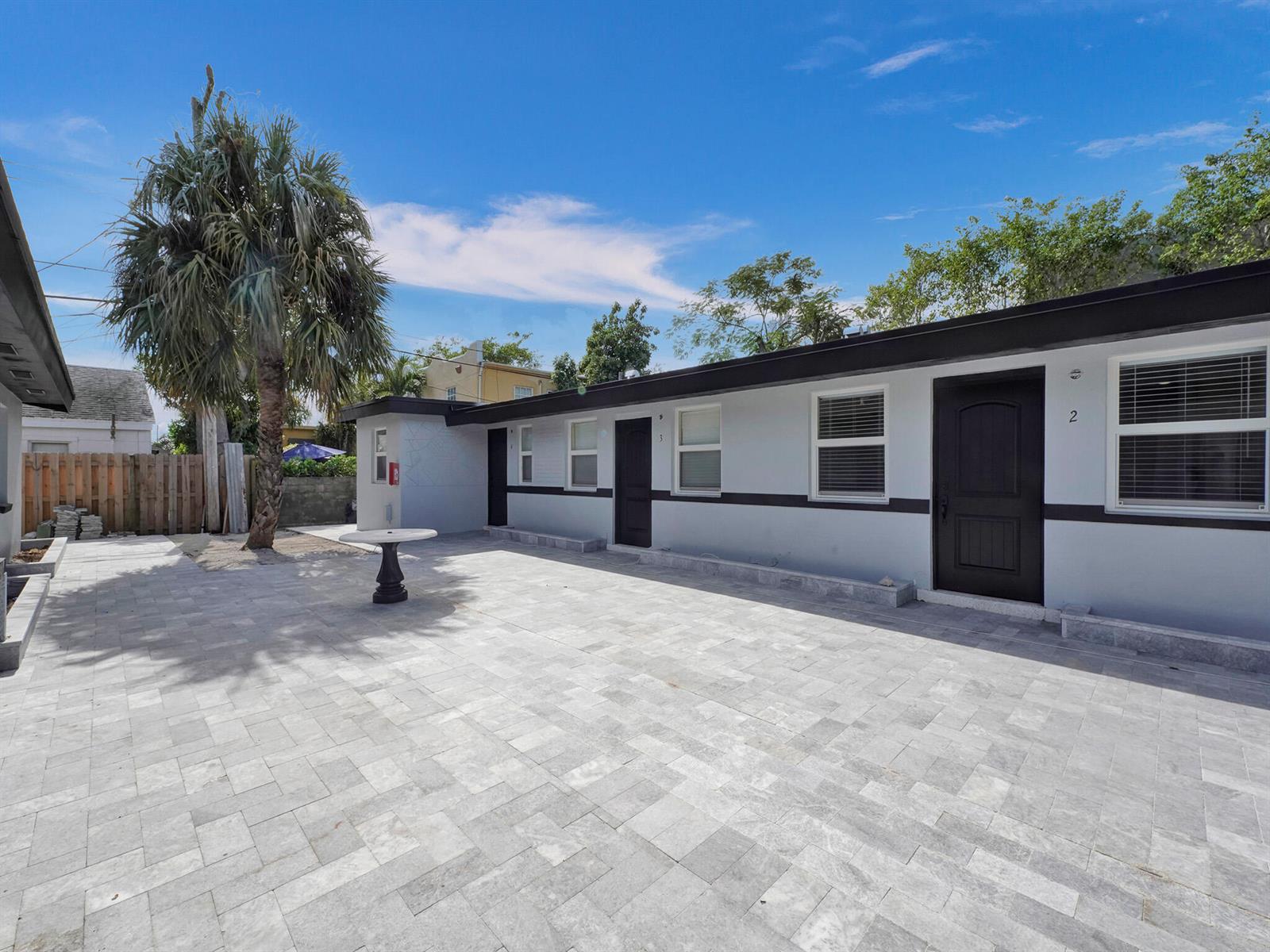 A paved courtyard sits in front of a single-story building with two dark entry doors — 332 Walton Boulevard, West Palm Beach FL 33405, WEST PALM BEACH, FL