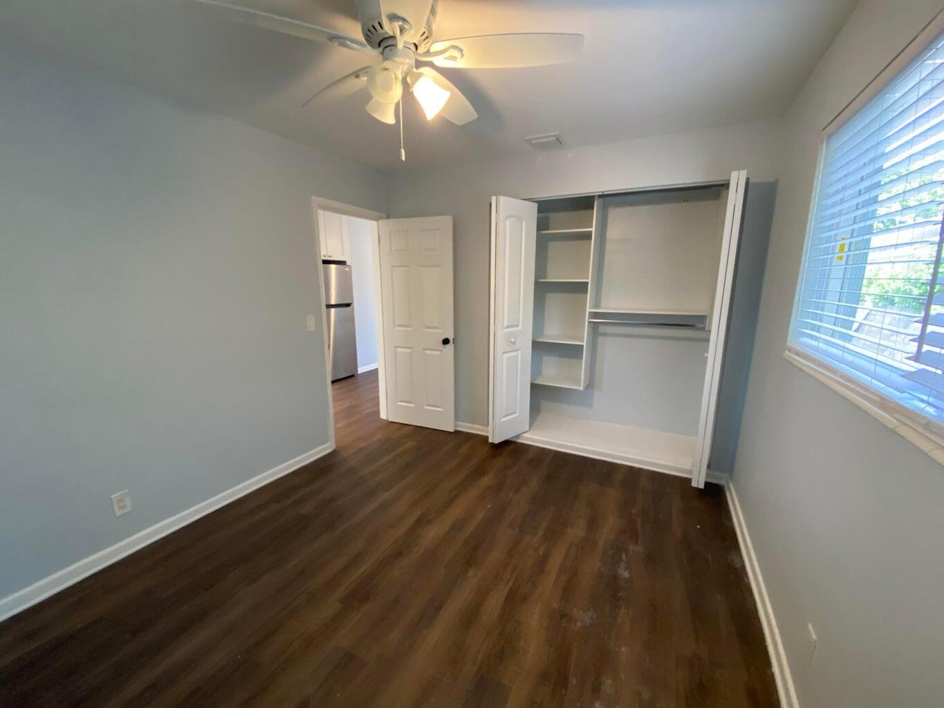 A bedroom with light blue walls, dark wood-look flooring, a ceiling fan, and a closet — 332 Walton Boulevard, West Palm Beach FL 33405, WEST PALM BEACH, FL