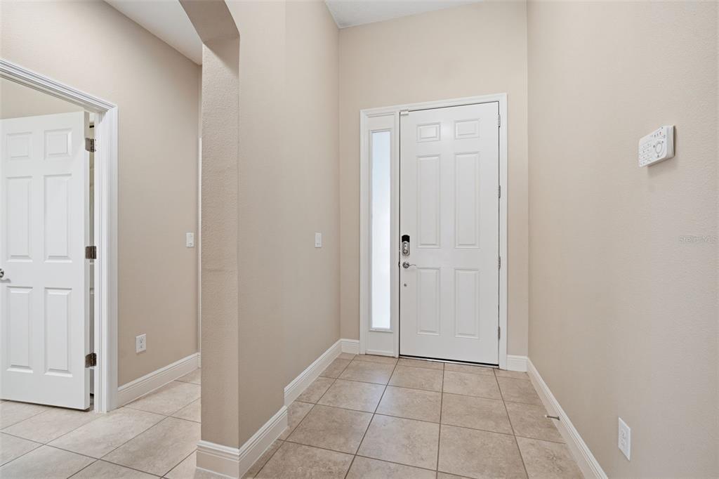 An entryway features beige walls, tiled flooring, a white front door, and an arched opening — 7316 HERMES COURT, APOLLO BEACH, FL