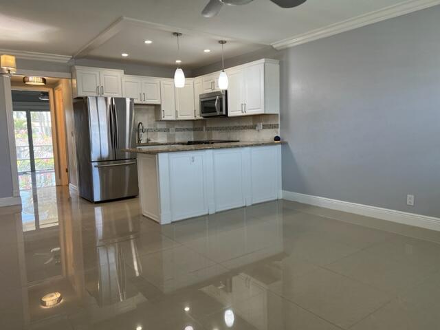 A kitchen with white cabinets, stainless steel appliances, and tile flooring opens to a room — 800 W Horizons W # 211, Boynton Beach FL 33435, BOYNTON BEACH, FL