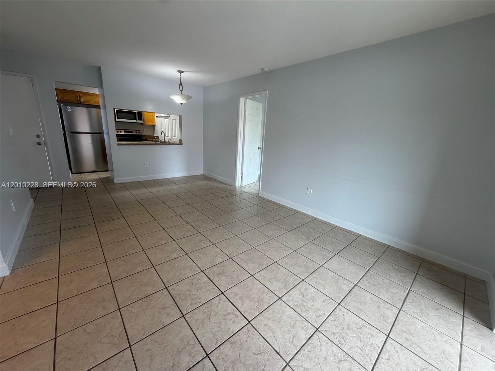 An open living area features light-colored tile flooring, pale blue walls, and a kitchen pass-through — 6540 W 27th Ct # 24, Hialeah FL 33016, HIALEAH, FL