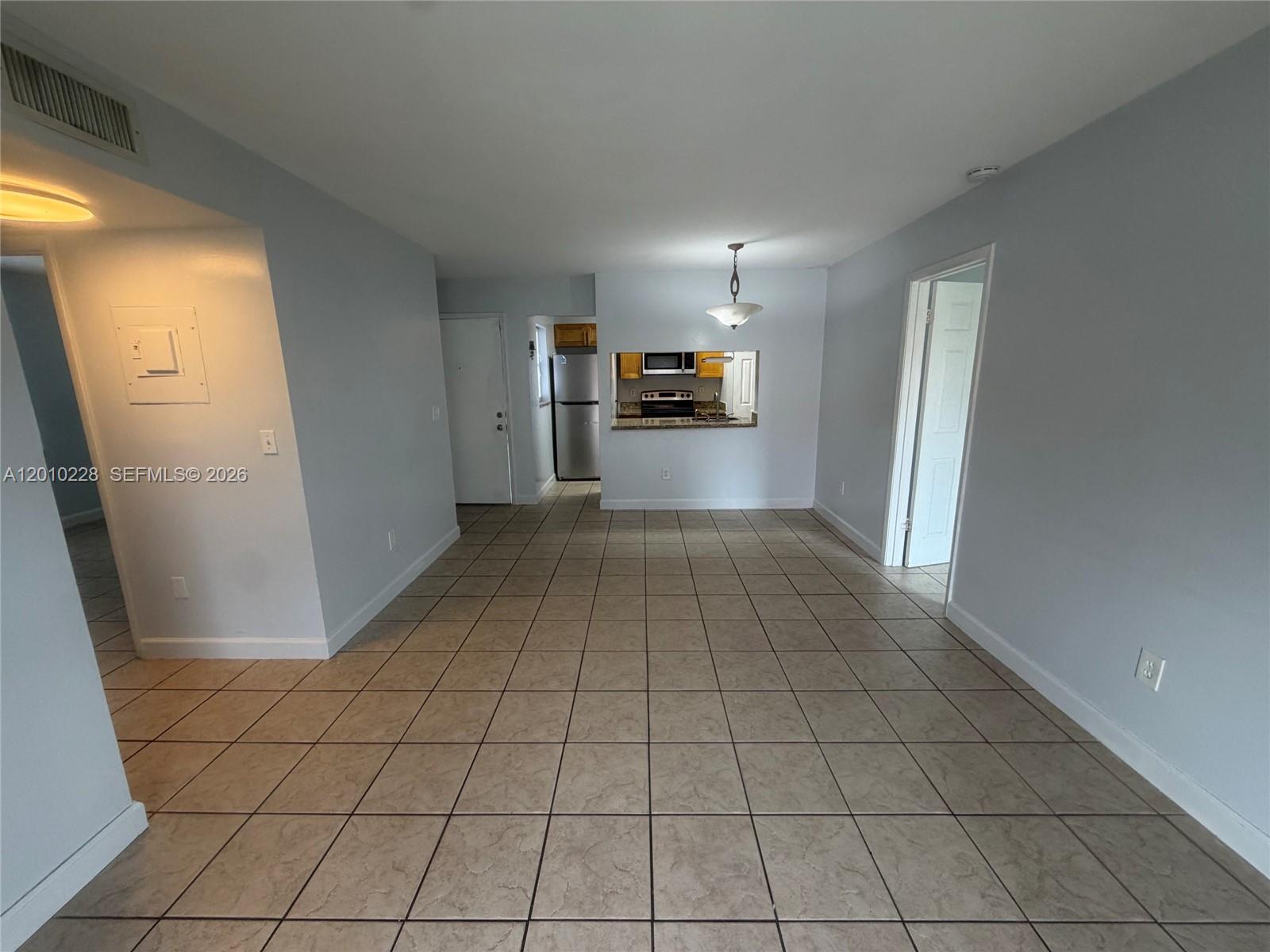 An open-concept living area features light gray walls, beige tile flooring, and a kitchen pass-through — 6540 W 27th Ct # 24, Hialeah FL 33016, HIALEAH, FL