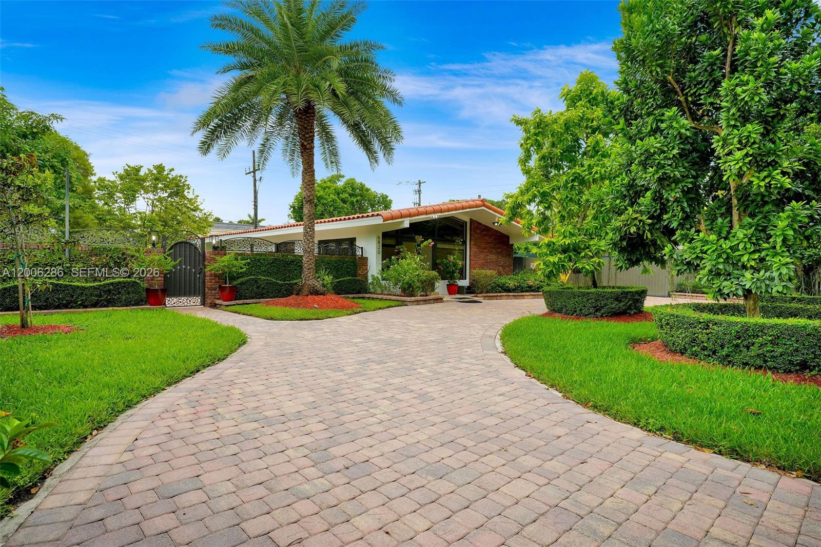 A single-story house with a brick facade and a paved driveway sits behind a gate — 6820 SW 86th Ave, Miami FL 33143, MIAMI, FL