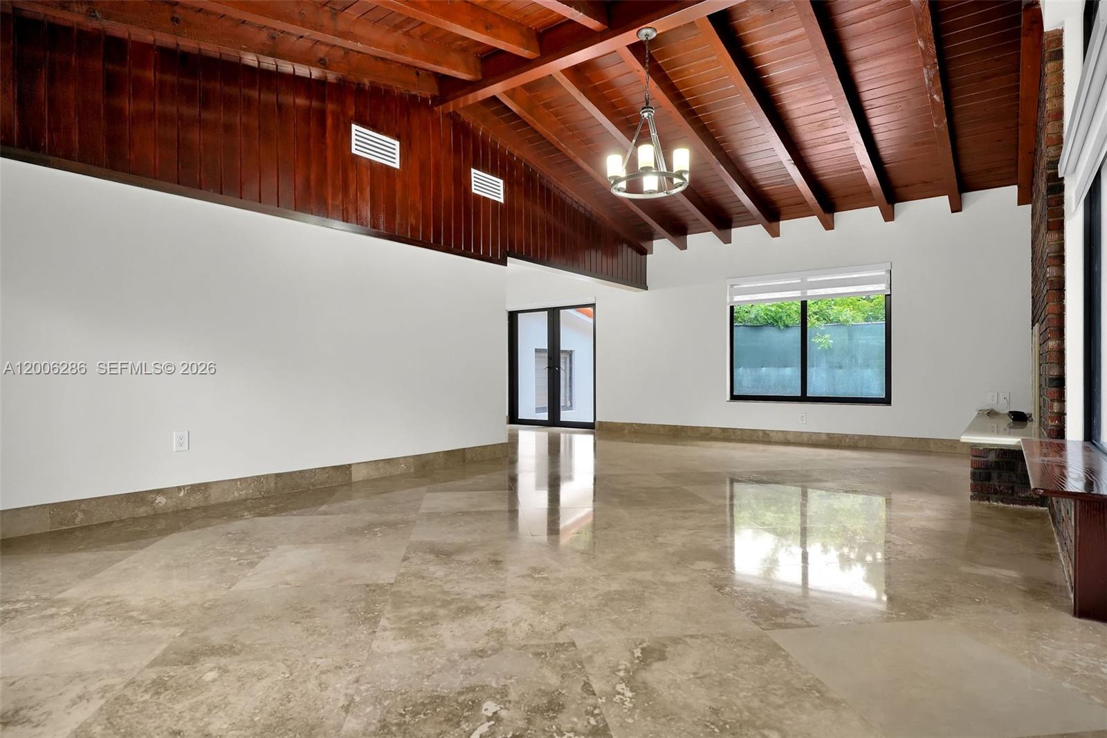 A spacious room features a vaulted wood-beamed ceiling, white walls, and polished stone flooring — 6820 SW 86th Ave, Miami FL 33143, MIAMI, FL
