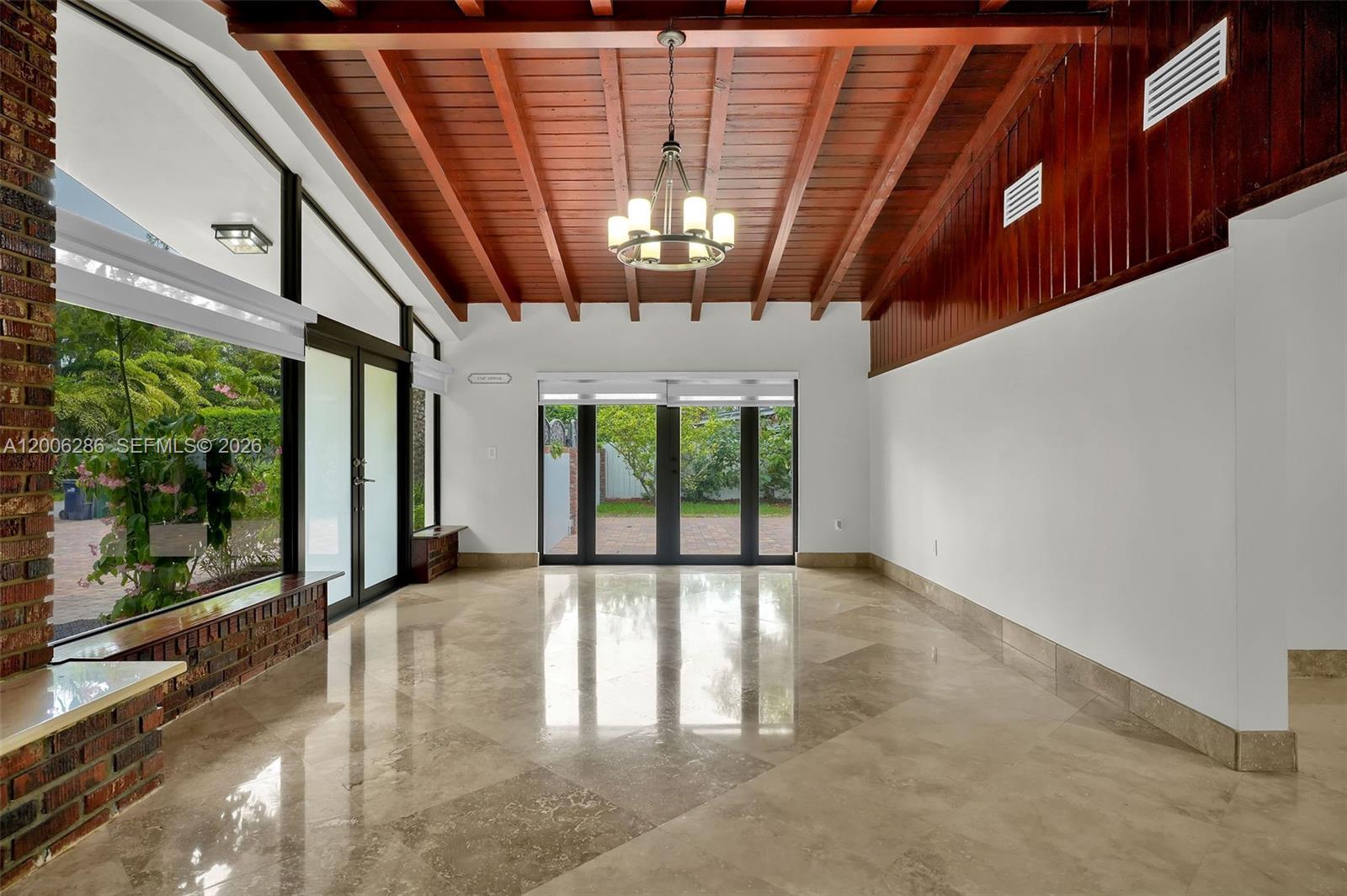 A sunroom features a wood-beamed ceiling, marble flooring, and large glass doors leading outside — 6820 SW 86th Ave, Miami FL 33143, MIAMI, FL