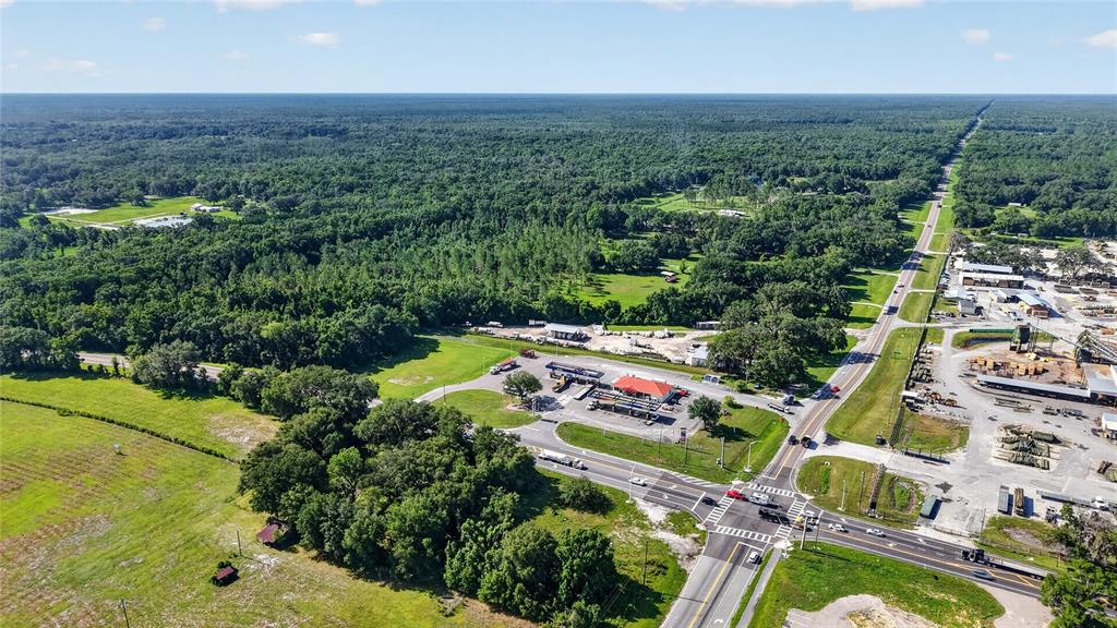 An aerial view shows a rural intersection with a gas station, industrial site, and forest — 13921 SR 471, WEBSTER, FL