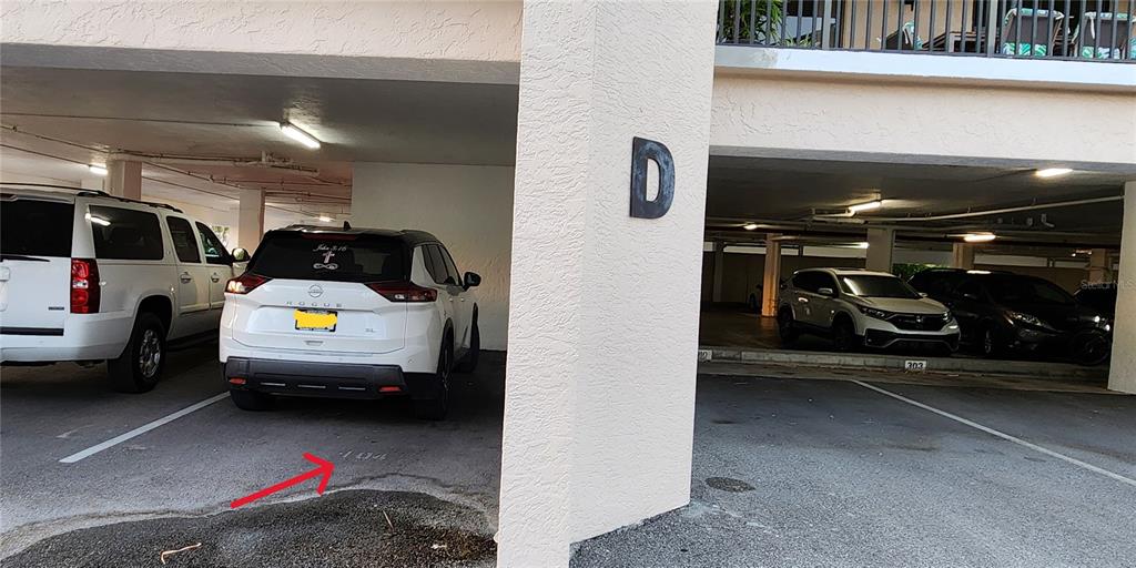 A covered parking area shows a white SUV parked in a numbered space near building D — 25188 MARION AVENUE UNIT D104, PUNTA GORDA, FL