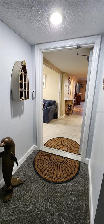 A doorway leads from a carpeted entryway with a dolphin statue into a tiled living area — 25188 MARION AVENUE UNIT D104, PUNTA GORDA, FL